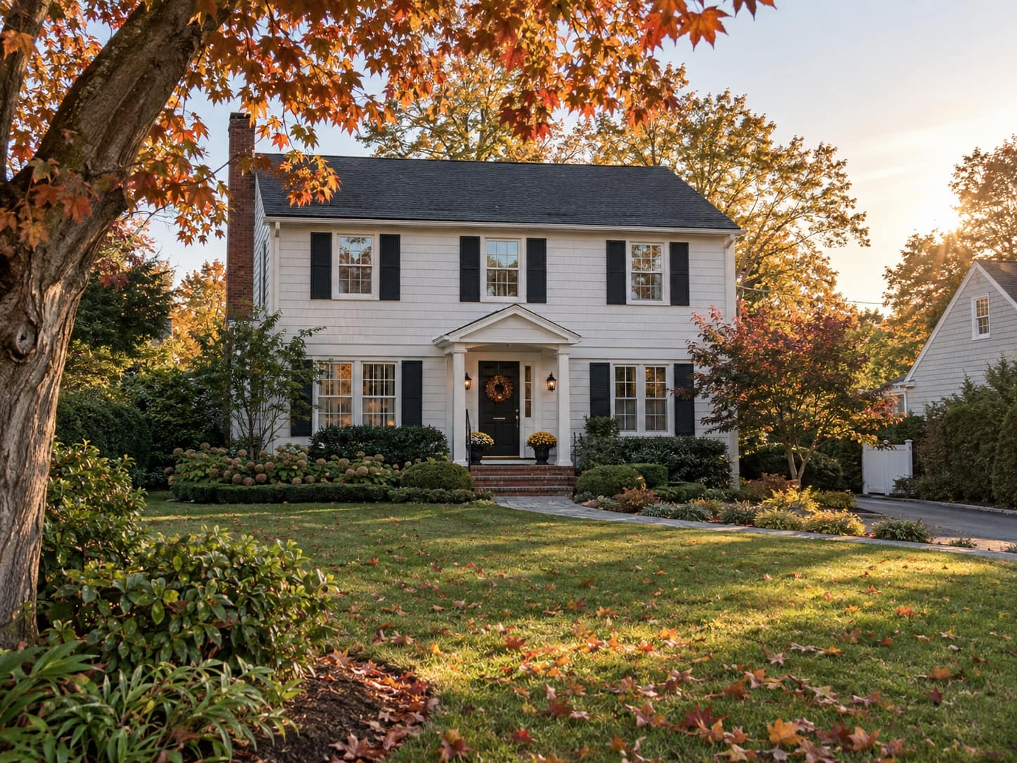 Long Island colonial house in early autumn with leaves turning and a few on the lawn, marking the weeks a listing sits on the market